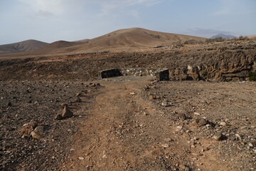 volcanic arid landscapes with trils, cliffs, and scattedred vegetation.