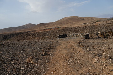 volcanic arid landscapes with trils, cliffs, and scattedred vegetation.