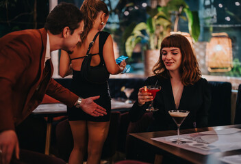 A group of friends having a fun night out, enjoying cocktails in a modern, stylish bar. The atmosphere is lively and vibrant, perfect for social gatherings and celebrations.