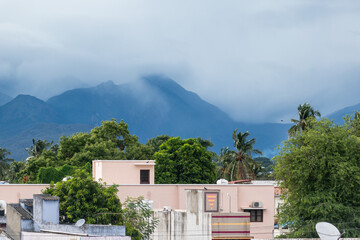 Majestic mountains loom over residential area in Madurai during overcast weather