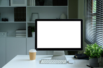 Modern desktop computer with blank screen on white desk in stylish home office