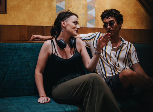 A young couple engaging in a casual conversation at a stylish cafe lounge. The relaxed atmosphere and trendy setting provide a sense of leisure and connection.