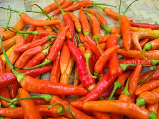 Close up of fresh red and orange chili peppers on traditional bamboo tray. 
