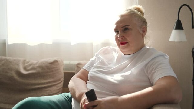 Elderly woman watching TV at home, laughing and enjoying the show. A joyful and emotional moment capturing relaxation, happiness, and the simple pleasures of daily life.

