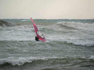 Water Sport Activity - Windsurfer Riding a Wave in Rough Sea on a Windy Day
