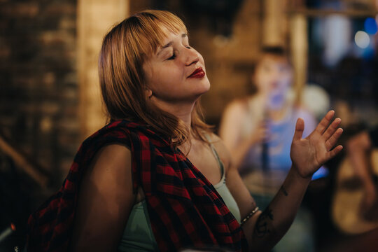 A woman with closed eyes and a blissful expression enjoying live music at an indoor event. Captures the relaxed and joyful atmosphere of the evening.