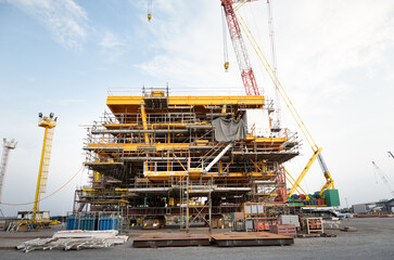 Oil rig construction onshore by crawler crane. Heavy industry and engineering technology for exploration and drilling crude in power fuel business investment.