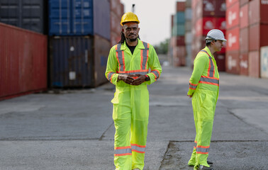 Industrial engineer standing at shipping container yard inspecting cargo delivering loading as plan. Cargo manager and diverse ethnic worker checking import export container at logistic terminal dock.