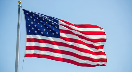 United States flag waving in the wind on a metal pole against a clear blue sky