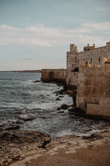 Sea with waves rolling next to Castello Maniace in Syracuse, Sicily