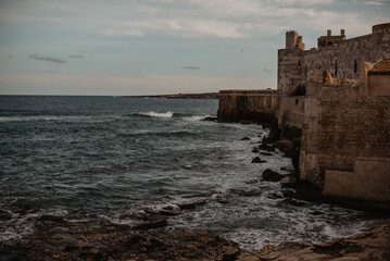 Sea with waves rolling next to Castello Maniace in Syracuse, Sicily