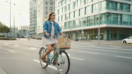 A woman enjoys a leisurely bike ride through a bustling city in the early morning. She carries a stylish eco-shopping bag, promoting sustainable living in an urban environment