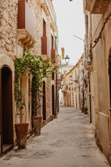 Charming narrow street in Syracuse, Sicily, with baroque stone buildings and Mediterranean character