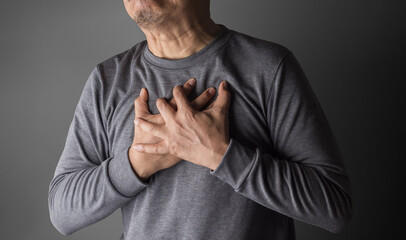 heart disease concept. asia old man pressing on chest with painful expression. severe heartache and having heart attack or painful cramps.