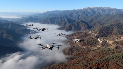 Drones flying over mountainous landscape during clear daytime with fog drifting below and trees showing autumn colors