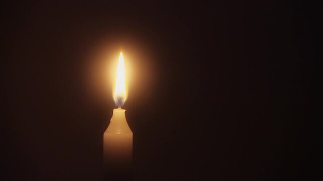 Close-up of male hands lighting a candle with matches, flame burning steadily in calm indoor setting