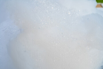 Close-up of frothy soap bubbles forming a foamy texture against a white background.