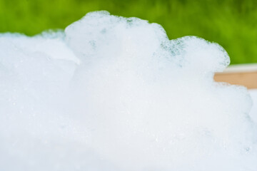 Close-up of frothy soap bubbles forming a foamy texture against a white background.
