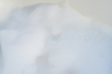 Close-up of frothy soap bubbles forming a foamy texture against a white background.