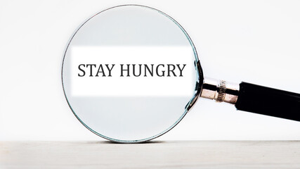 Concept Phase STAY HUNGRY focused through a magnifying glass