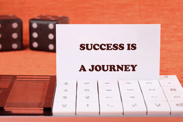 Concept text SUCCESS IS A JOURNEY on a business card with game cubes in the background and a...