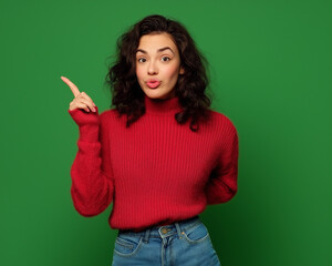 Full-Body Portrait of a Happy Woman in a Red Sweater and Blue Jeans, Pointing to the Side on a Green Background – Studio-Quality Lighting, Perfect for Advertising & Marketing