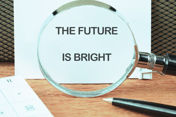 THE FUTURE IS BRIGHT concept words focused on the notebook through a magnifying glass