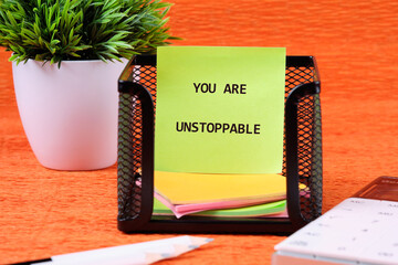Concept text YOU ARE UNSTOPPABLE written on colorful stickers in a black mesh holder