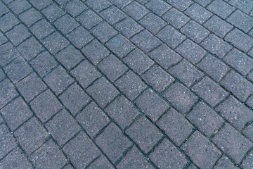 Textured grey road pavers are laid as a road base in a pattern formation.
