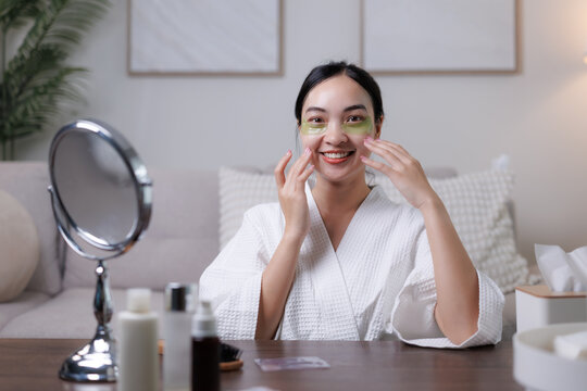 Smiling woman applying eye patches at home