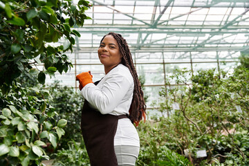 Empowered gardener tending to vibrant plants under greenhouse canopy