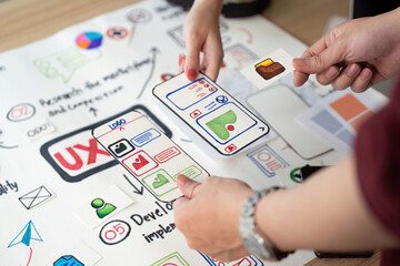 Collaborative UX Design. Team members discussing user interface elements on design board.