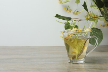 cup of herbal tea with linden flowers on wooden background