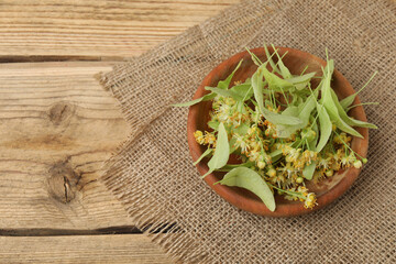 cup of herbal tea with linden flowers on wooden background