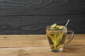 cup of herbal tea with linden flowers on wooden background