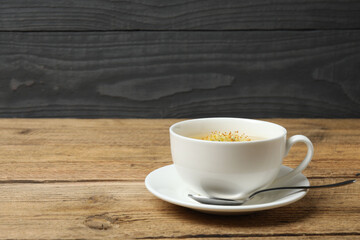 cup of herbal tea with linden flowers on wooden background