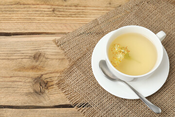 cup of herbal tea with linden flowers on wooden background
