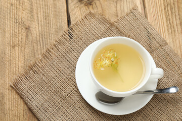 cup of herbal tea with linden flowers on wooden background