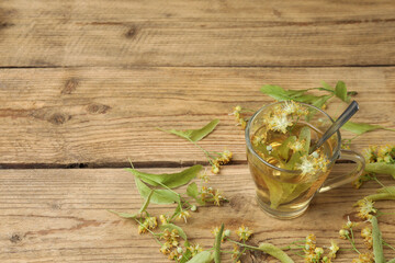 cup of herbal tea with linden flowers on wooden background