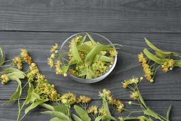 cup of herbal tea with linden flowers on wooden background
