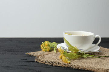 cup of herbal tea with linden flowers on wooden background