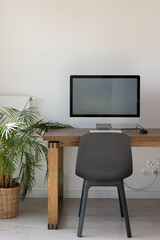 modern bright workplace with desktop computer on wooden table, office workplace with white wall, vertical with copyspace