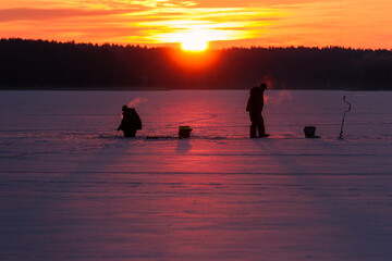 Silhouettes of Fishermen on Frozen Lake in Backlight Early in the Morning