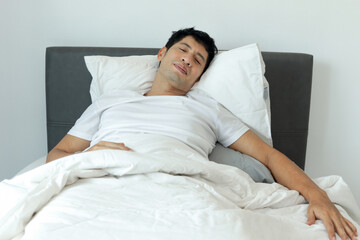 Asian man sleeping on comfortable bed in the morning in his bedroom. A man sleeps soundly and...