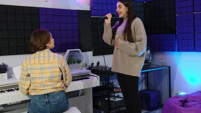 Female teacher makes rich sounds with piano enriching student vocal. Woman singer musical horizons expand broadening artistic perspective slow motion