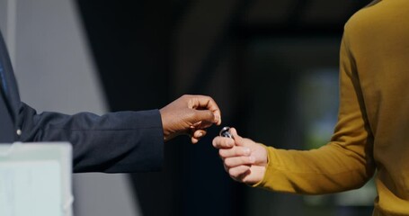 The realtor hands over the keys to the buyer of the property. They are standing outside the house on a summer day. Close-up of their hands, unrecognizable persons