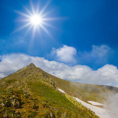 mountain ridge in dense mist and clouds under a sparkle sun
