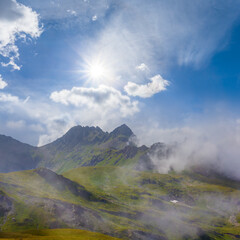 mountain ridge in dense mist and clouds under a sparkle sun