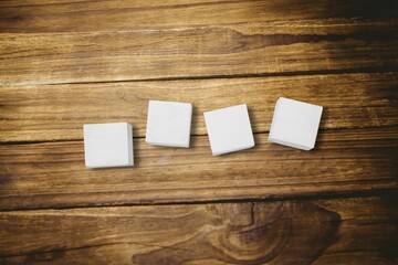 Four white cubes are sitting on wooden tabletop in flat design showing grain patterns, shadows © vectorfusionart
