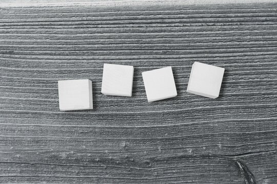 Fototapeta Four white square blocks are being arranged in line on wood surface with grain, flat design